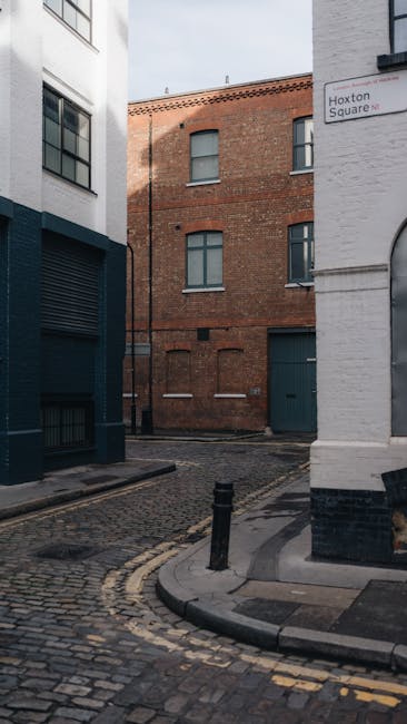 The image shows the exterior of a white-painted brick building with an arched, black-framed window occupying most of the visible wall space. Below the window, there is a black brick section that appea